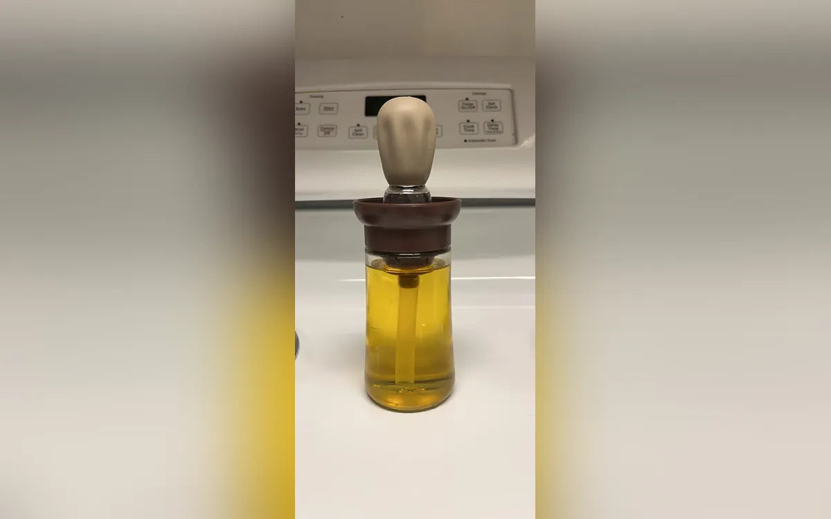 Aceitera con brocha llena de aceite sobre una cocina, foto de Juliana S.